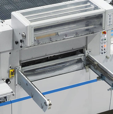 Side view of a heavy-duty foil stamping press showing safety guards and emergency stop button